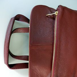 Un modelo de mochila de piel de mujer y posibilidad de hacerlo en bandolera con bolsillos y de color guinda