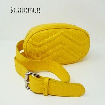 Una riñonera para mujer de piel con hebilla para regularla y cierre con cremallera y forma ovalada de color amarillo